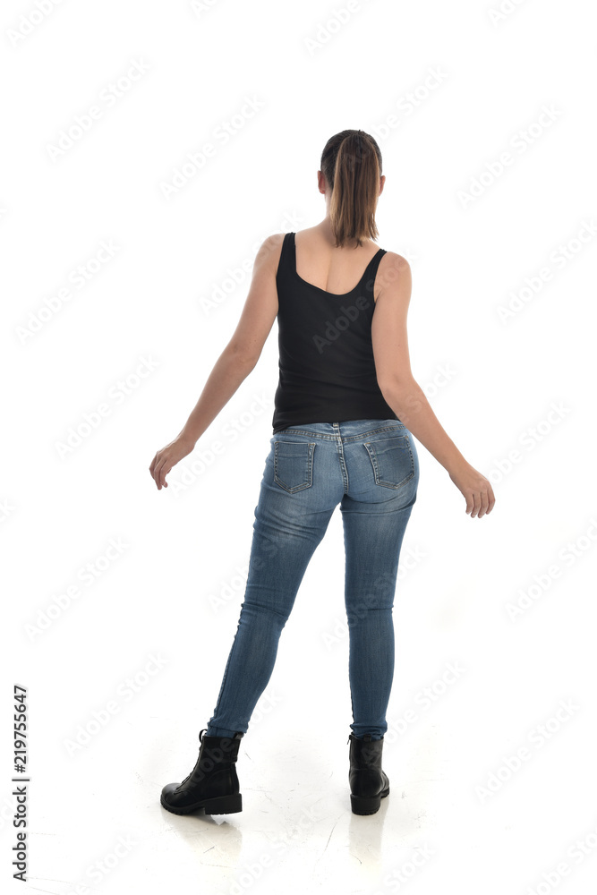 full length portrait of brunette girl wearing black single and jeans. standing pose with back to the camera. isolated on white studio background. full length portrait of brunette girl wearing black single and jeans. standing pose with back to the camera. isolated on white studio background.