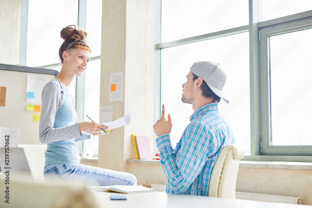 Positive hipster colleagues discussing company development and offering creative ideas while working in modern office Positive hipster colleagues discussing company development and offering creative ideas while working in modern office