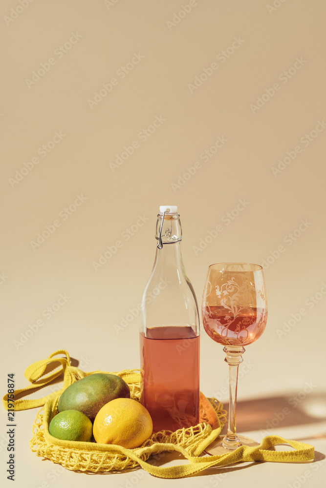 close-up view of drink in glass and bottle, string bag and fresh fruits on brown close-up view of drink in glass and bottle, string bag and fresh fruits on brown