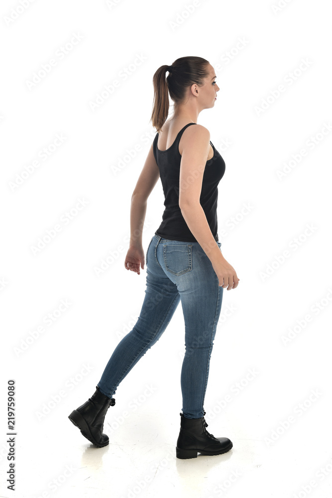 full length portrait of brunette girl wearing black single and jeans. standing pose with back to the camera. isolated on white studio background. full length portrait of brunette girl wearing black single and jeans. standing pose with back to the camera. isolated on white studio background.