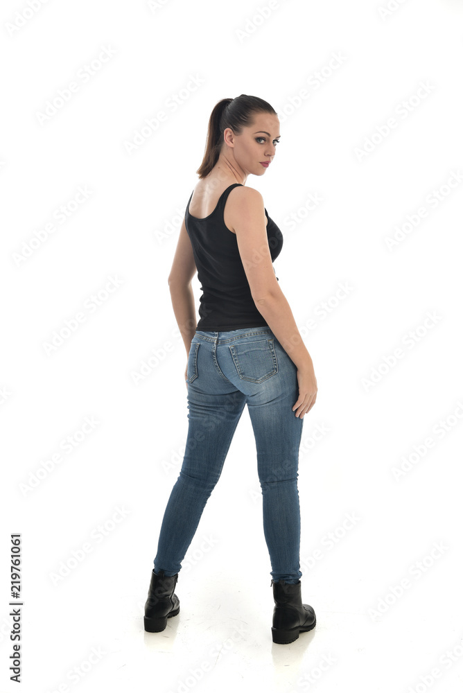 full length portrait of brunette girl wearing black single and jeans. standing pose with back to the camera. isolated on white studio background. full length portrait of brunette girl wearing black single and jeans. standing pose with back to the camera. isolated on white studio background.
