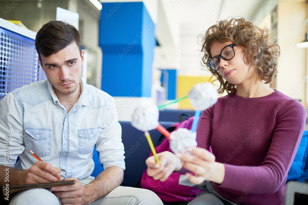 Obraz premium Young tutor explaining the structure of molecule to the man while he making notes in his notebook