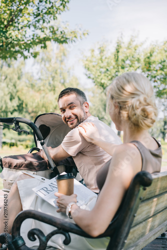 Photos wife sitting near baby carriage with coffee to go and travel newspaper and looki