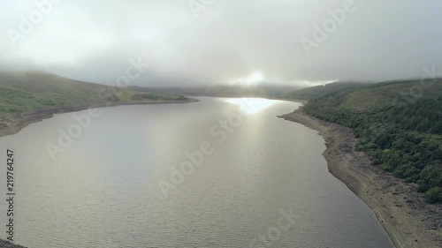 Aerial view, fast pan move. Drone panorama of Llyn Celyn water reservoir with dam and sheep on grass in Wales photo