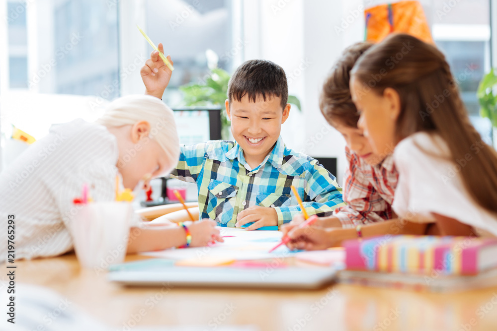 Fototapeta premium Spare time. Excited joyful kids drawing while spending time together at school
