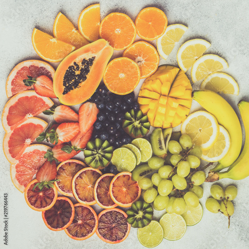 Table top view of healthy fruits in rainbow colours, arranged in a circle, strawberries, mango, grapes, bananas, grapefruit on the light table, selective focus, square. Toned photo