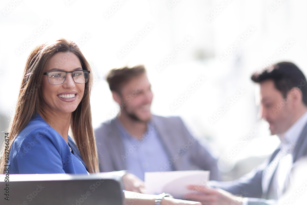 business woman sitting at a table on the background of colleagues business woman sitting at a table on the background of colleagues