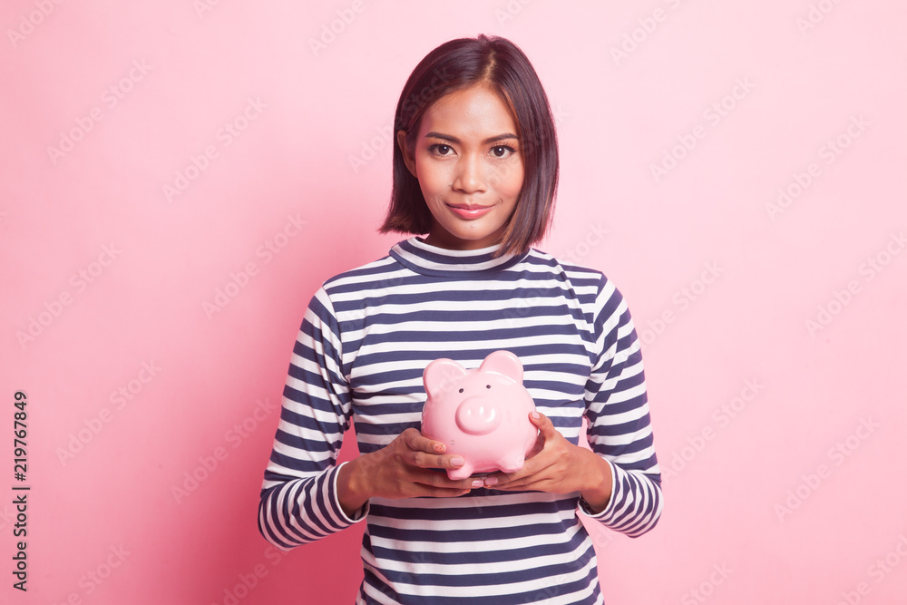 Young Asian woman with a pig coin bank. Young Asian woman with a pig coin bank.