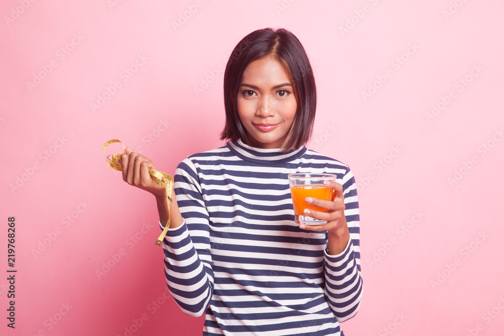 Asian woman drink orange juice hold measuring tape. Asian woman drink orange juice hold measuring tape.