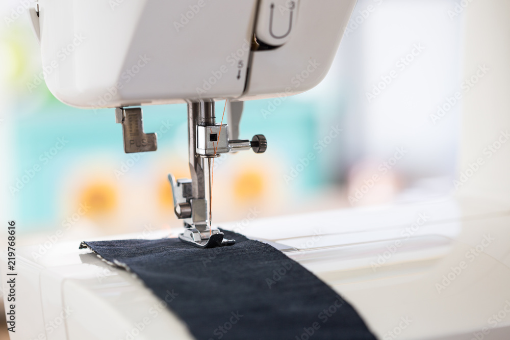 sewing machine with colour thread and needle on a table with blurred background, Tailor's work table, textile or fine cloth making, industrial fabric, home appliances tool.