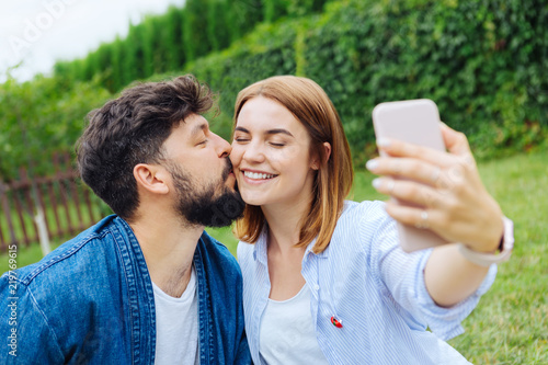 Selfie with man. Beaming blonde-haired woman feeling extremely happy while making selfie with her man