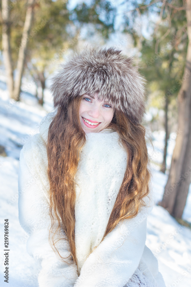 Girl in a white fur coat and a fur hat, with blue eyes and long hair  against the background of snow and trees. Winter Stock Photo | Adobe Stock