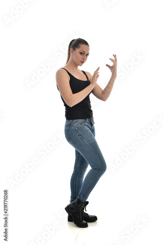 full length portrait of brunette girl wearing black single and jeans. standing pose facing the camera. isolated on white studio background. © faestock