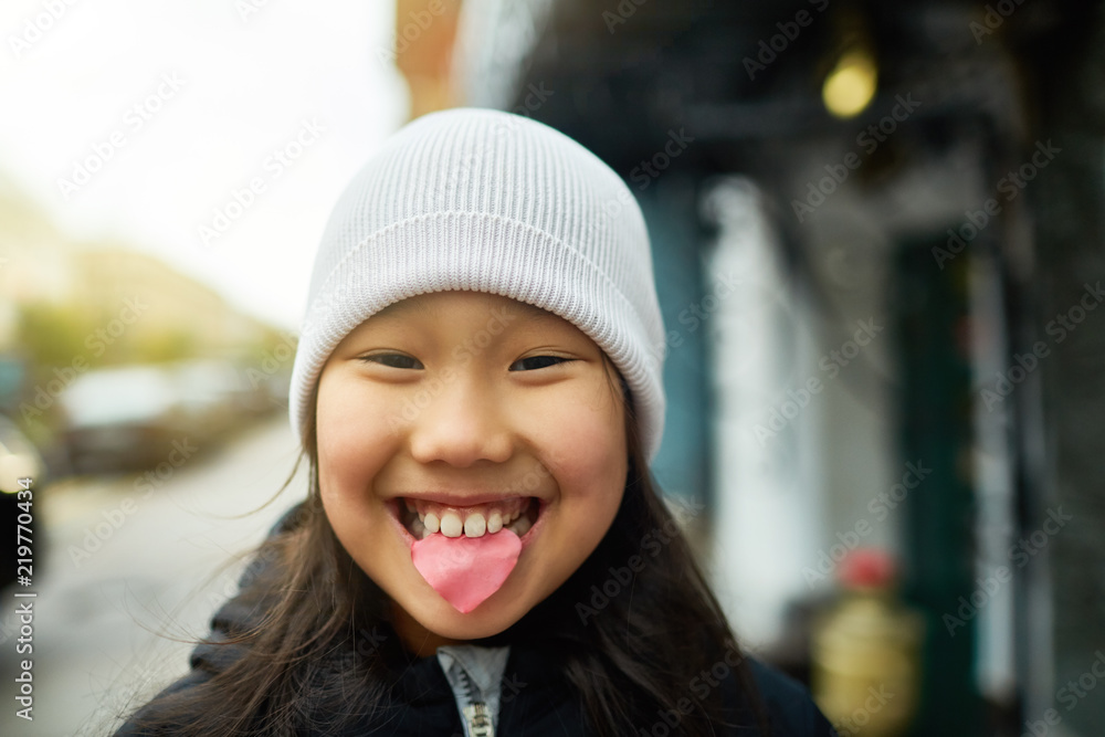 Joyful and funny girl with pink flower petal between her teeth and toothy smile looking at you Joyful and funny girl with pink flower petal between her teeth and toothy smile looking at you