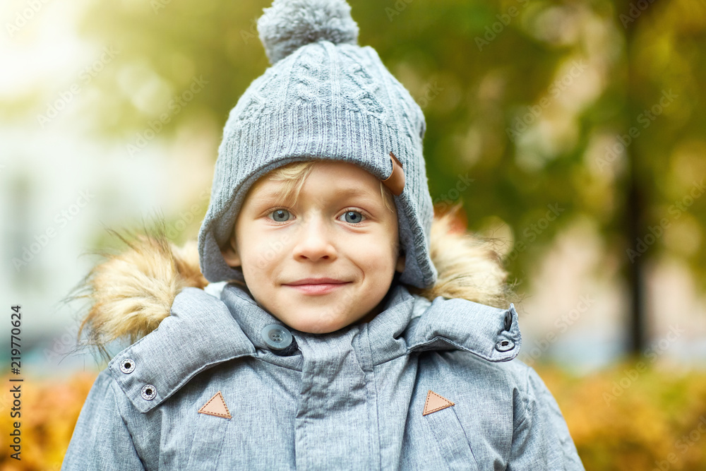 Cute boy with blue eyes and blond hair wearing warm grey jacket and knitted beanie Cute boy with blue eyes and blond hair wearing warm grey jacket and knitted beanie