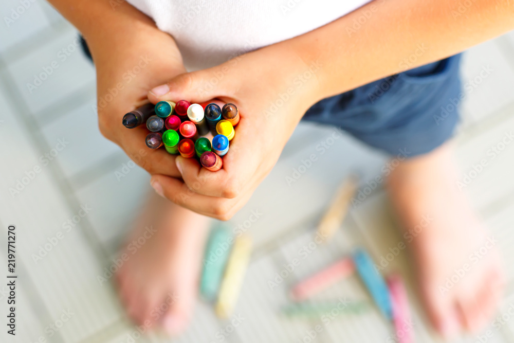 Close-up of child's hands with lots of colorful wax crayons pencils. Kid preparing school and nursery equipment and student stuff. Back to school. Education, school, learning concept.. Close-up of child's hands with lots of colorful wax crayons pencils. Kid preparing school and nursery equipment and student stuff. Back to school. Education, school, learning concept..