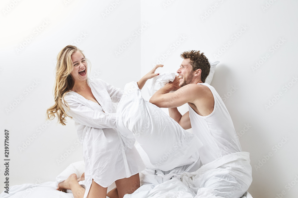 Young couple pillow fighting in bedroom Young couple pillow fighting in bedroom