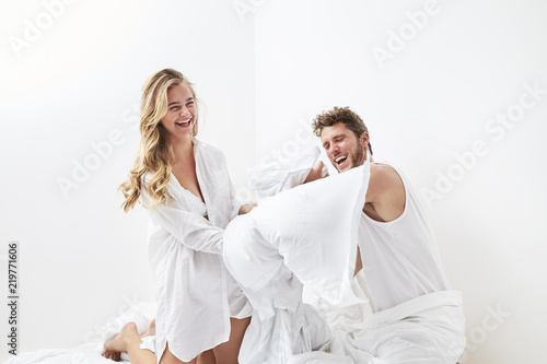 Pillow fighting young couple on bed