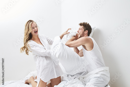Young couple pillow fighting in bedroom