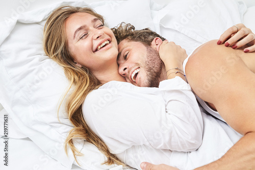 Smiling young couple relaxing in bed