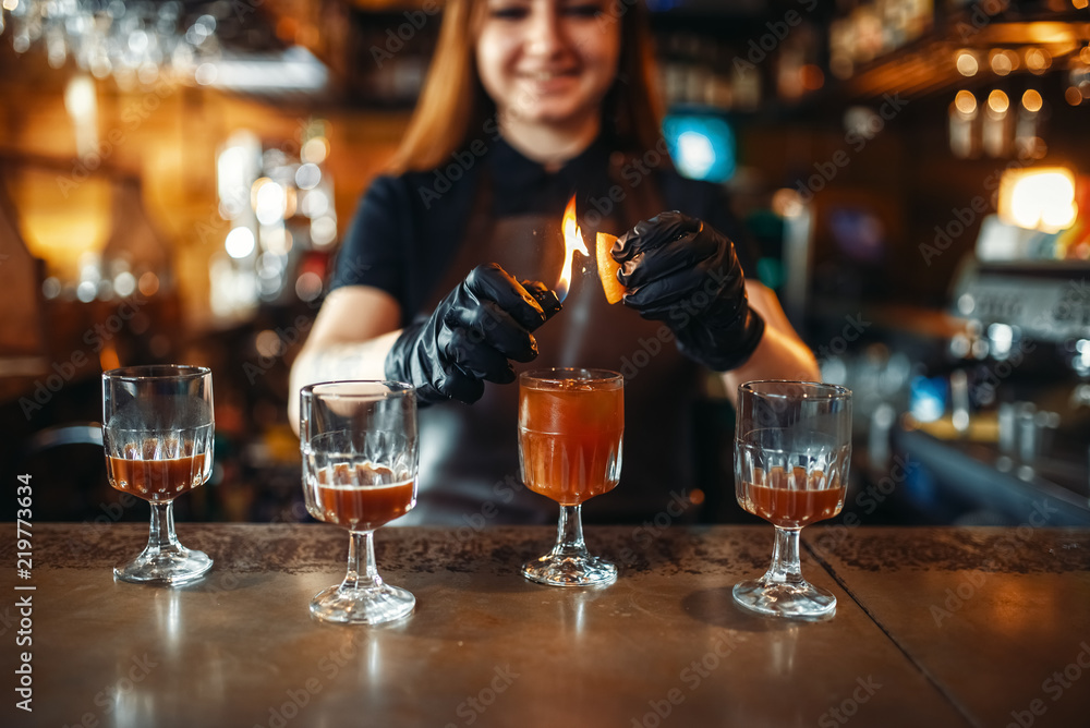 Female bartender making coctail with use of fire