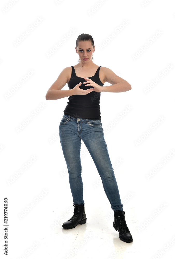 full length portrait of brunette girl wearing black single and jeans. standing pose facing the camera. isolated on white studio background. full length portrait of brunette girl wearing black single and jeans. standing pose facing the camera. isolated on white studio background.