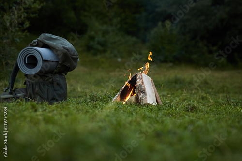 View of backpack and campfire in summer forest photo