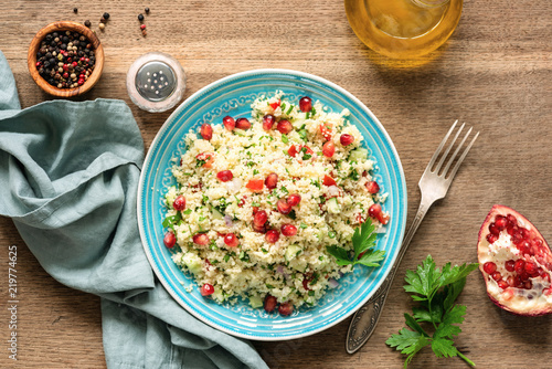 Couscous salad Tabbouleh with pomegranate seeds served on traditional turquoise plate. Arabic food photo
