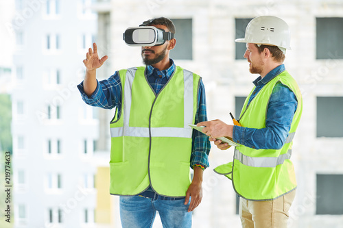 Konstfotografi Waist up portrait of two modern construction workers using VR gear to visualize
