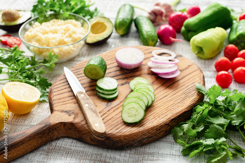 Fresh vegetables on cutting board. Cucumber, onion, pepper, parsley, radish avocado bulgur Preparing salad