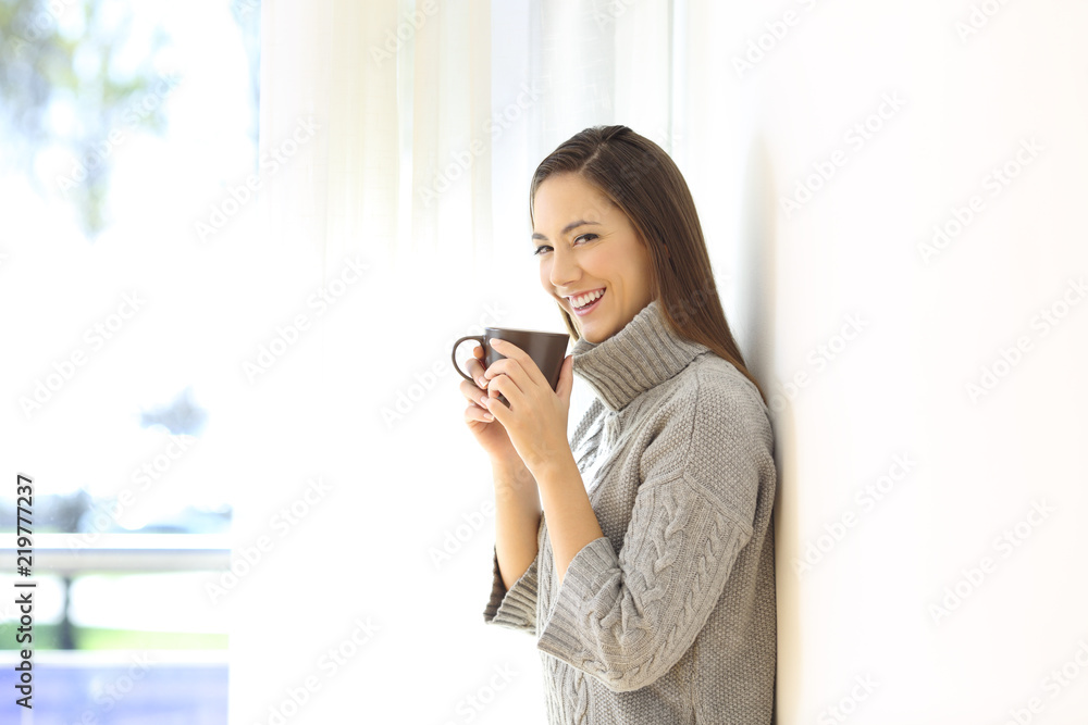 Happy girl looking at camera holding a coffee mug Happy girl looking at camera holding a coffee mug