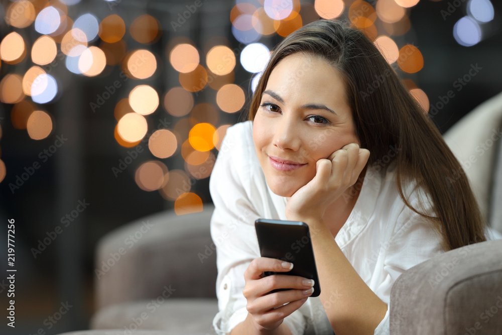 Relaxed girl looking at camera holding a phone Relaxed girl looking at camera holding a phone