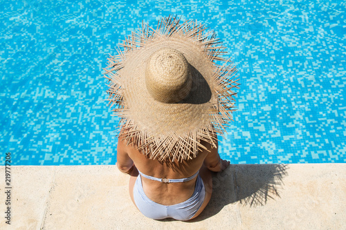 Mujer con sombrero de paja sentada en la piscina