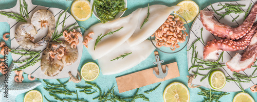 Various seafood: octopus , shrimp, squid and seaweed on light blue background with ingredients, top view. Seafood concept