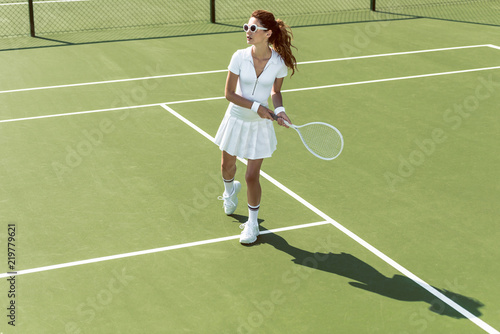side view of young attractive woman in white tennis uniform playing tennis on court © LIGHTFIELD STUDIOS