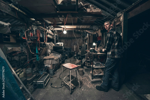 Obraz na płótnie Young man standing inside dark messy barn. w salonie