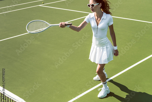 beautiful woman on white sportswear and sunglasses playing tennis on court