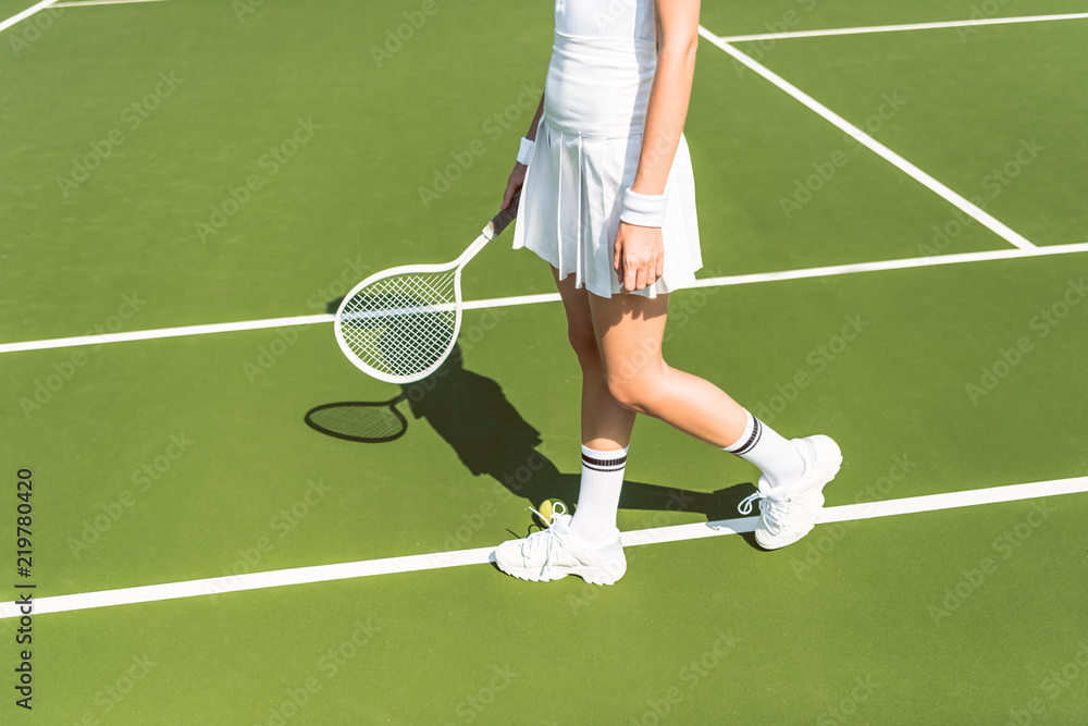 partial view of female tennis player in white sportswear with racket on tennis court