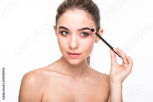 Beautiful woman using mascara of appealing brunette girl on white background