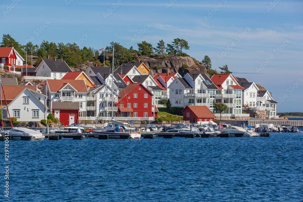 The traditional coastal wooden houses covered in sunlight in the Lyngor archipelago, Southern Norway