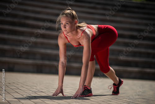 Beautiful young woman in start position in stadium in summer