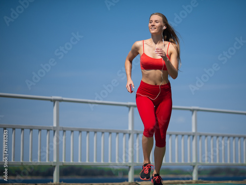 Fototapeta Naklejka Na Ścianę i Meble -  Young fitness woman running on the coast. The concept of a healthy lifestyle