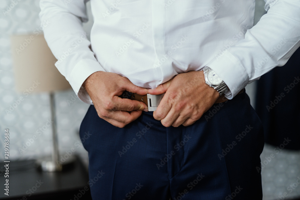 Mans hands putting belt on pant. Official dress up. Mans hands putting belt on pant. Official dress up.