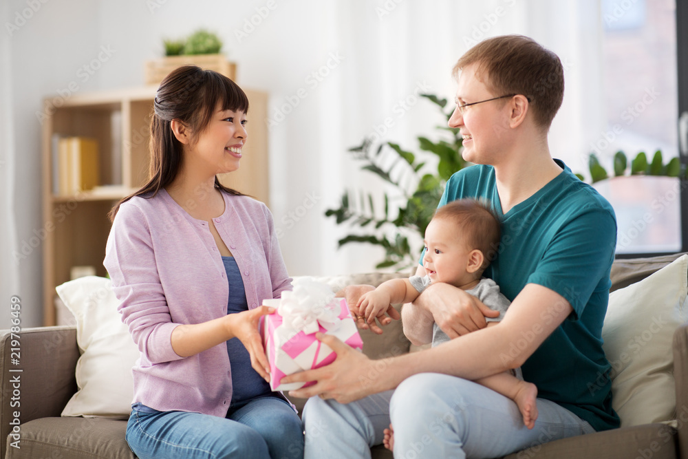 family, parenthood and mothers day concept - happy mother receiving gift box from father and baby boy at home family, parenthood and mothers day concept - happy mother receiving gift box from father and baby boy at home