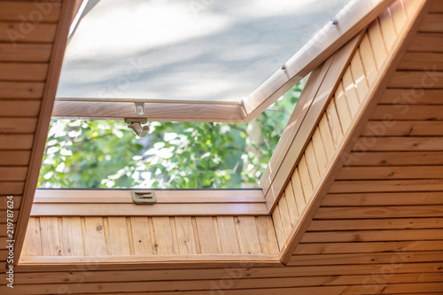 Quadro em tela Opened roof window with blinds or curtain in wooden house attic