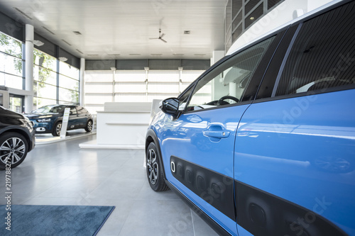 Close-up of a side door of a blue car on a spacious display in a showroom © Photographee.eu