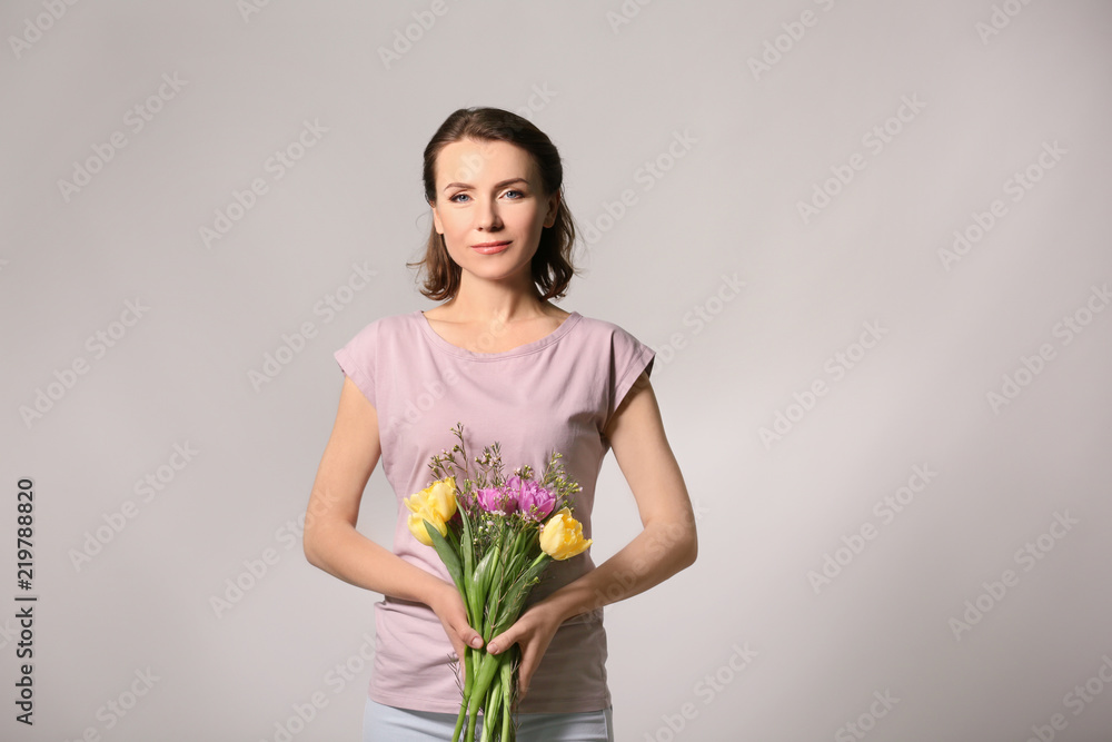 Beautiful woman with bouquet of flowers on light background Beautiful woman with bouquet of flowers on light background