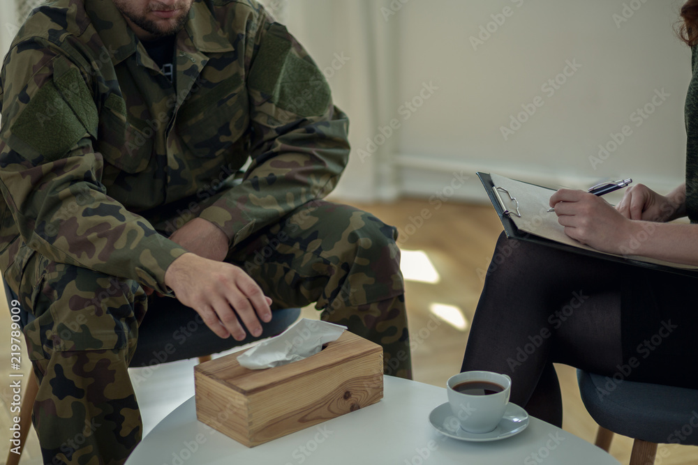 Close-up on crying soldier reaching for a tissue during consultation with therapist
