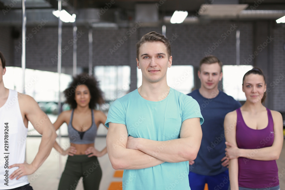 Sporty man with group of athletes in gym