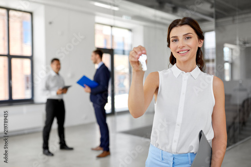 real estate business, sale and people concept - smiling realtor with keys and folder and customers at new office